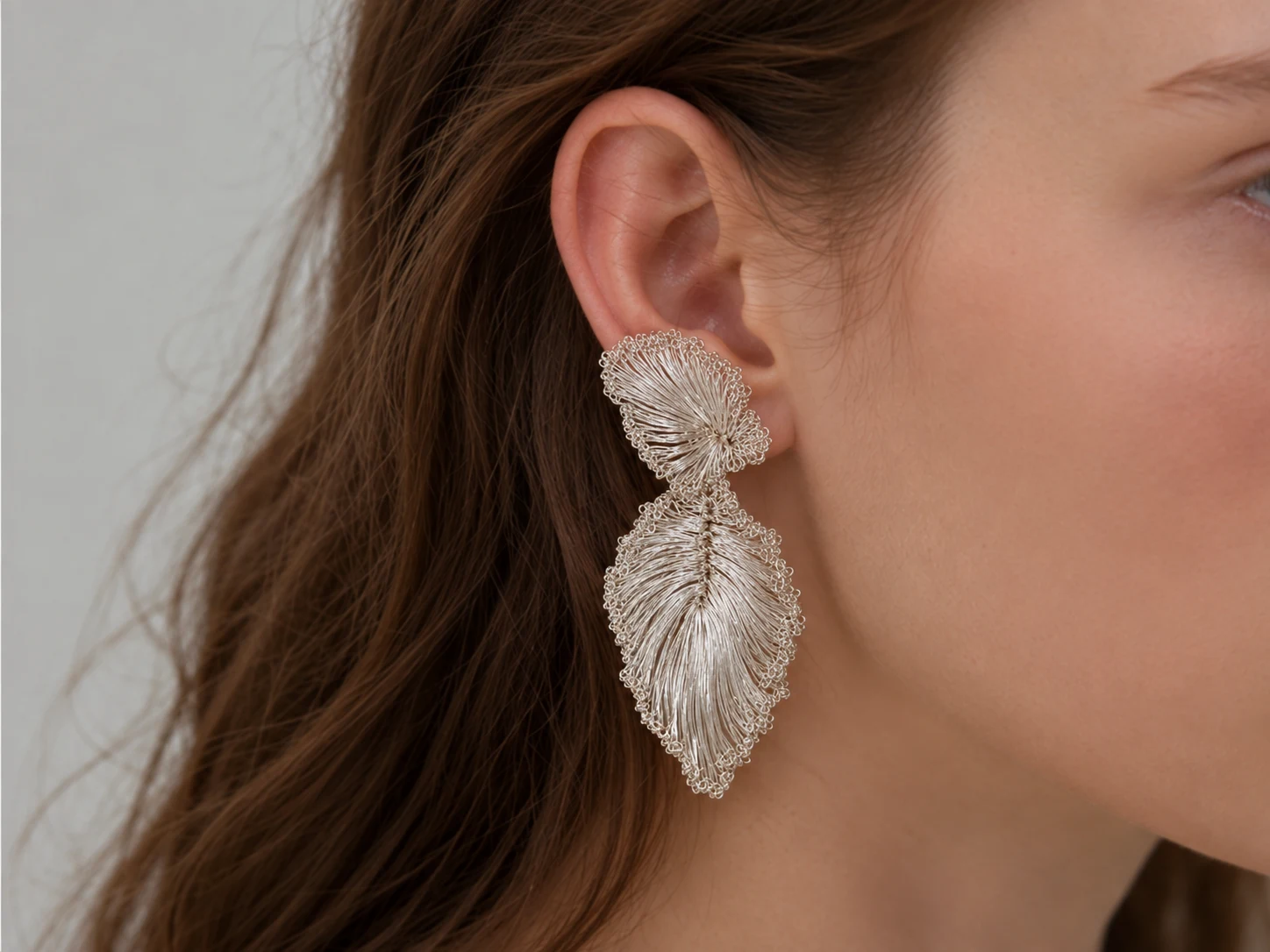 Handwoven ginkgo leaf statement earrings worn on the ear
