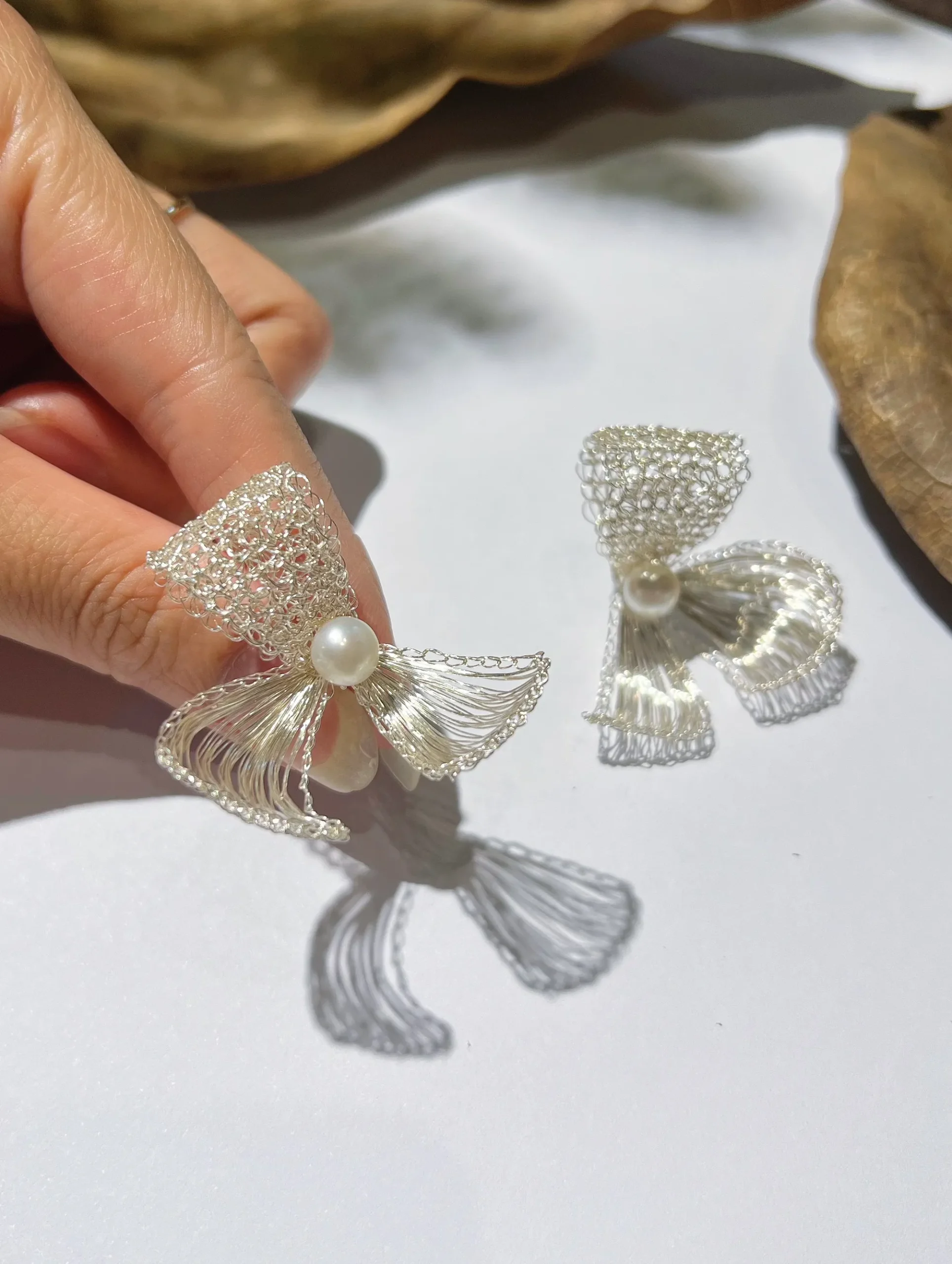 Close-up of handmade silver-tone wire bow earrings