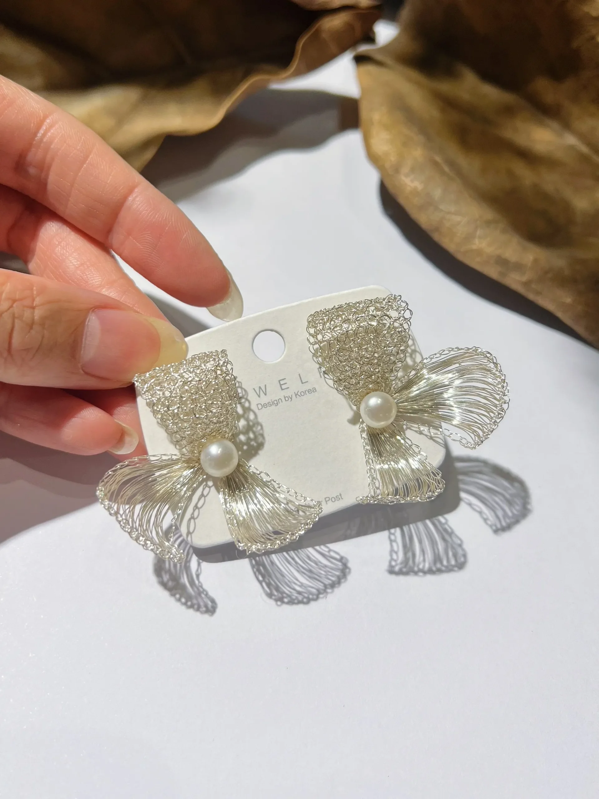 Handwoven silver-tone bow earrings with pearl-look centers