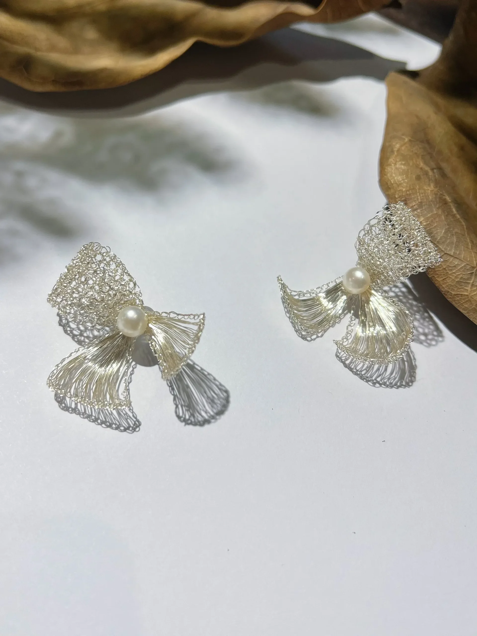 Pair of handmade silver-tone wire bow earrings with pearl-look centers