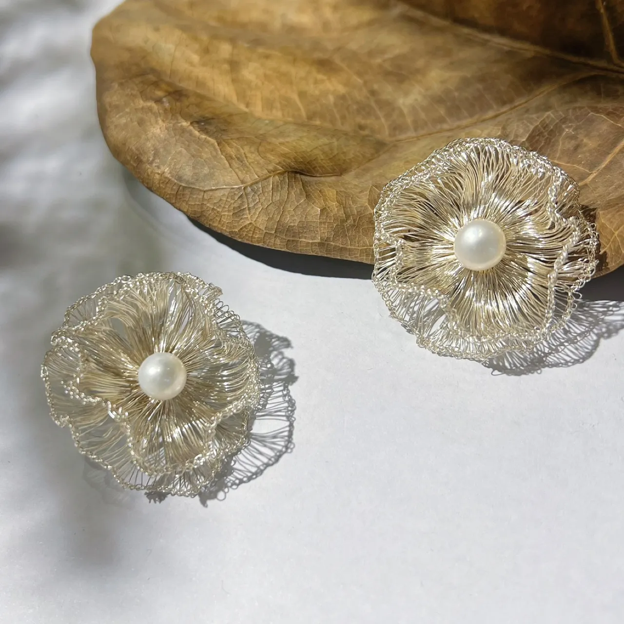 Pair of handwoven silver-tone wire flower earrings with pearl-look centers