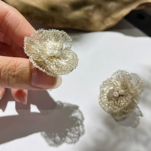 Close-up of handmade silver-tone wire flower earrings with pearl-look bead clusters