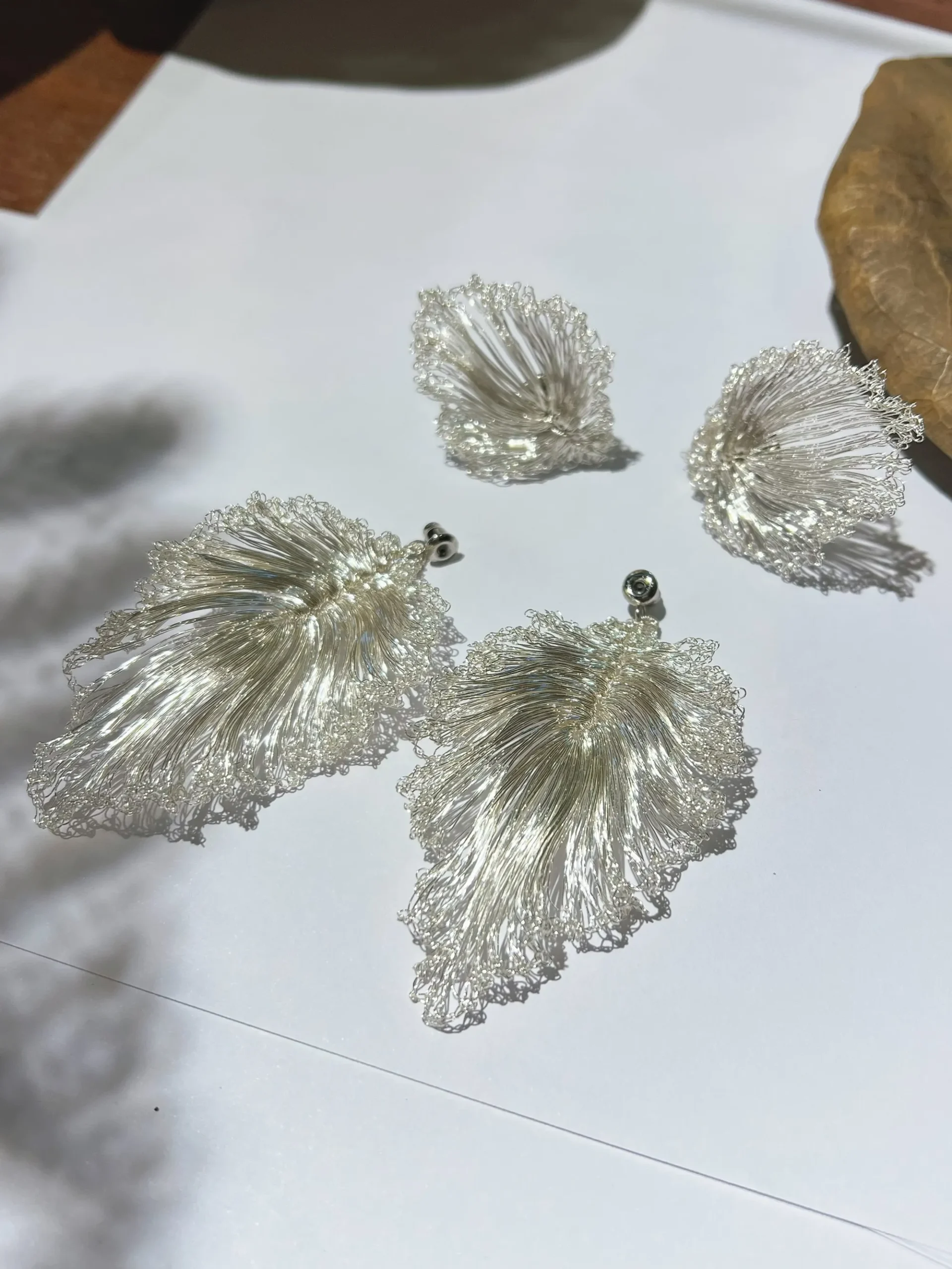 Handwoven wire leaf earrings displayed in the Tapurea studio