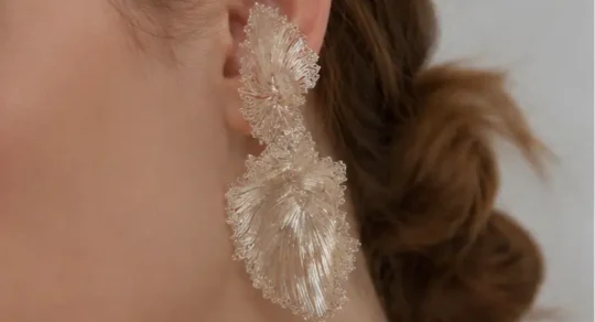 Woman wearing OREYNE fan palm leaf earrings