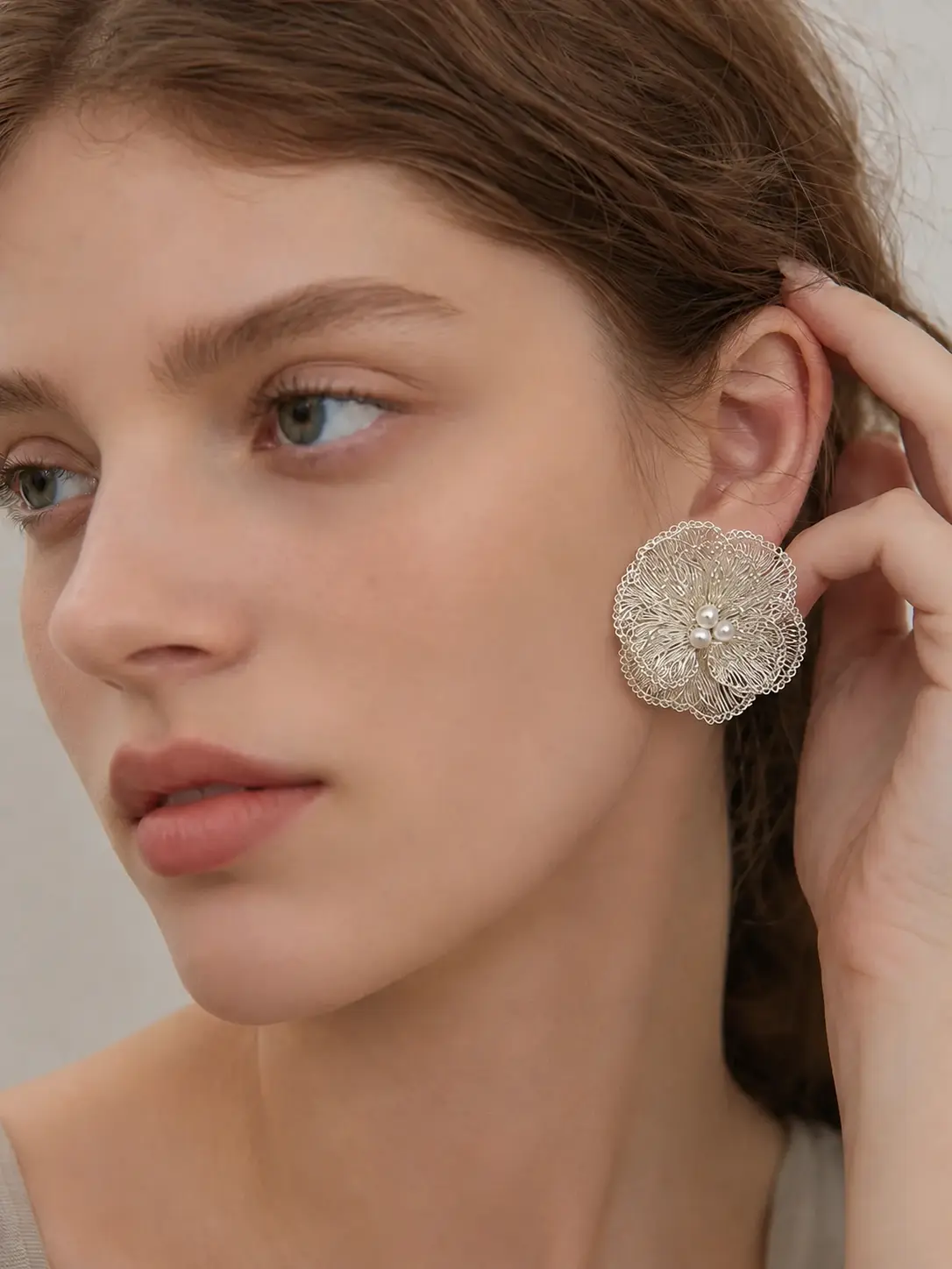 Woman wearing a handmade openwork flower statement earring with pearl-look accents