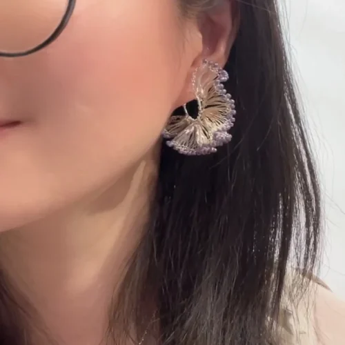 Woman wearing a purple beaded silver-tone ginkgo hoop earring