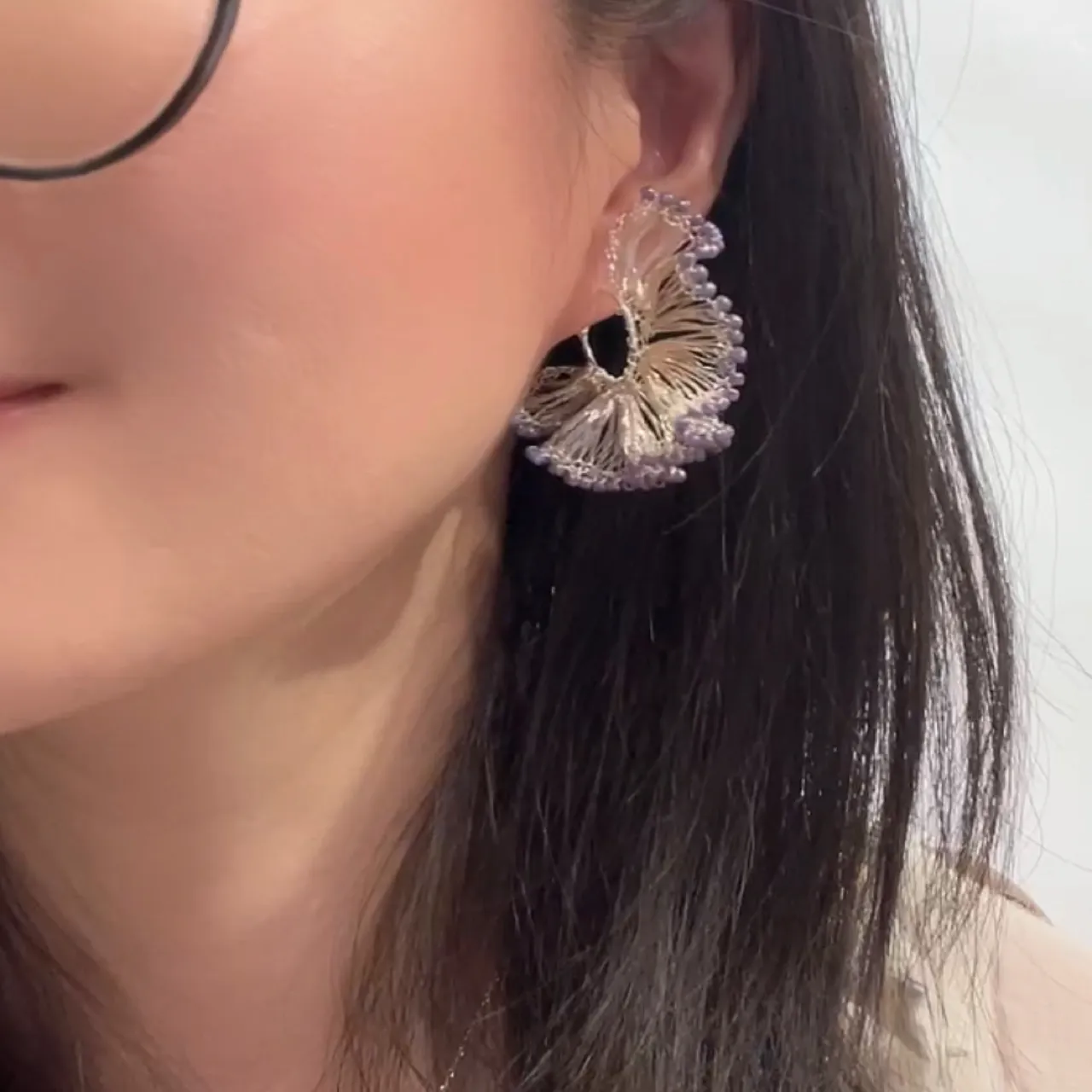 Woman wearing a purple beaded ginkgo hoop earring