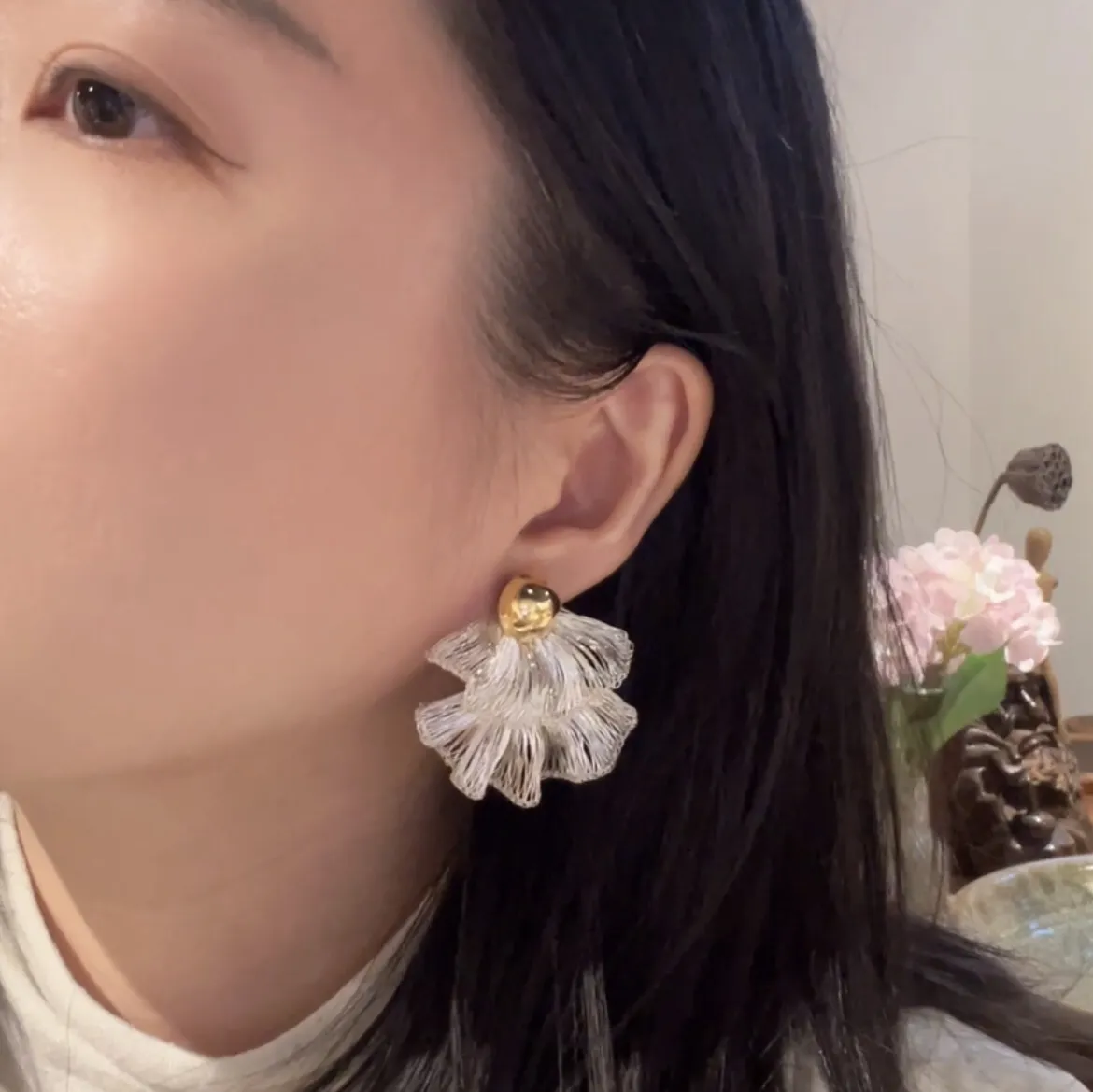 Woman wearing a sculptural silver-tone wire fan earring with layered petals
