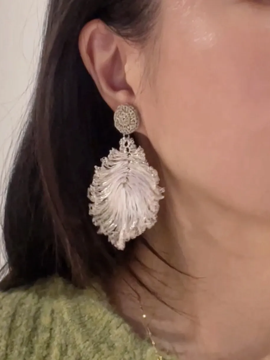Woman wearing a sculptural silver-tone wire leaf drop earring