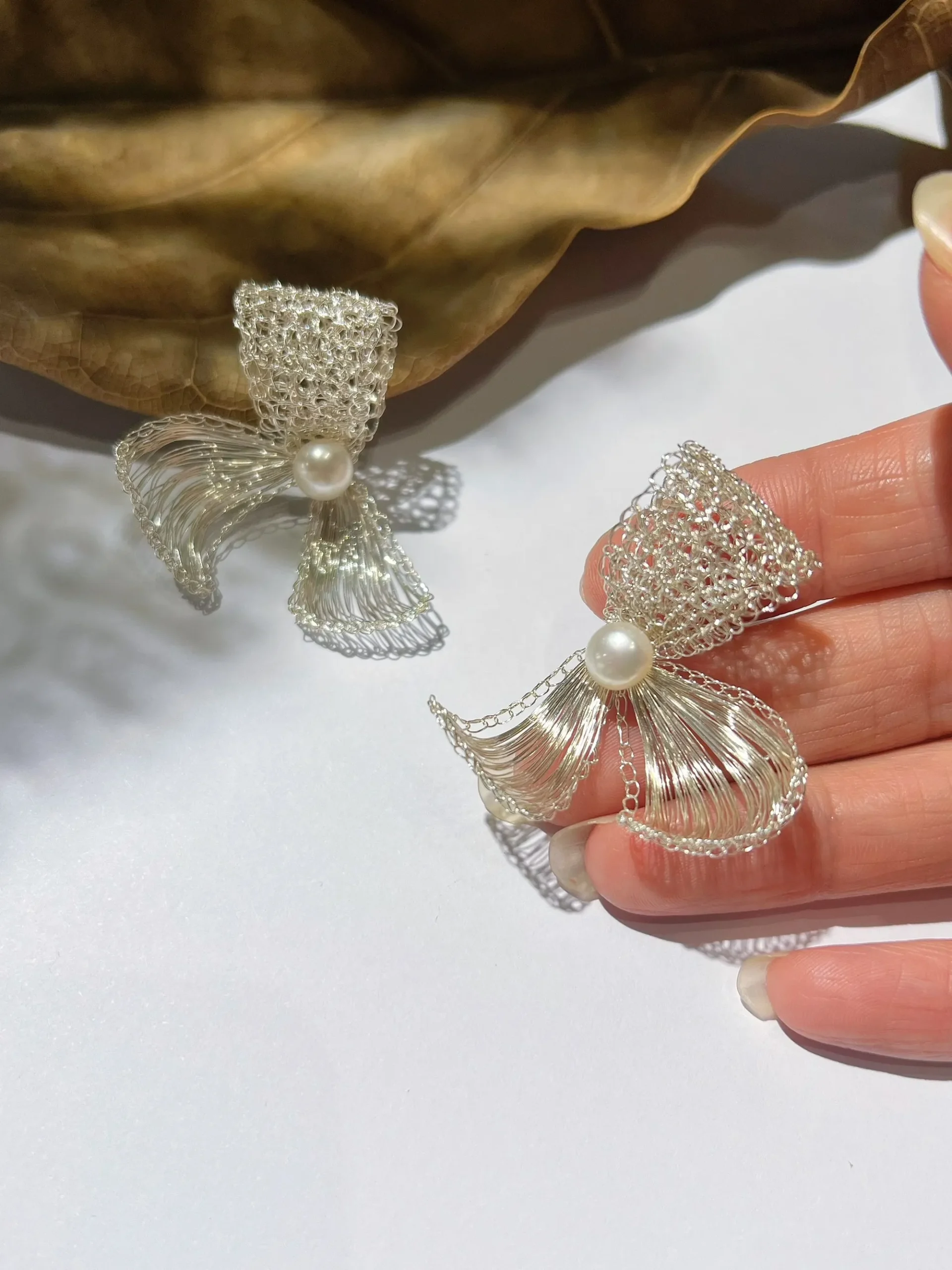 Handwoven silver-tone wire bow earrings with soft curved structure