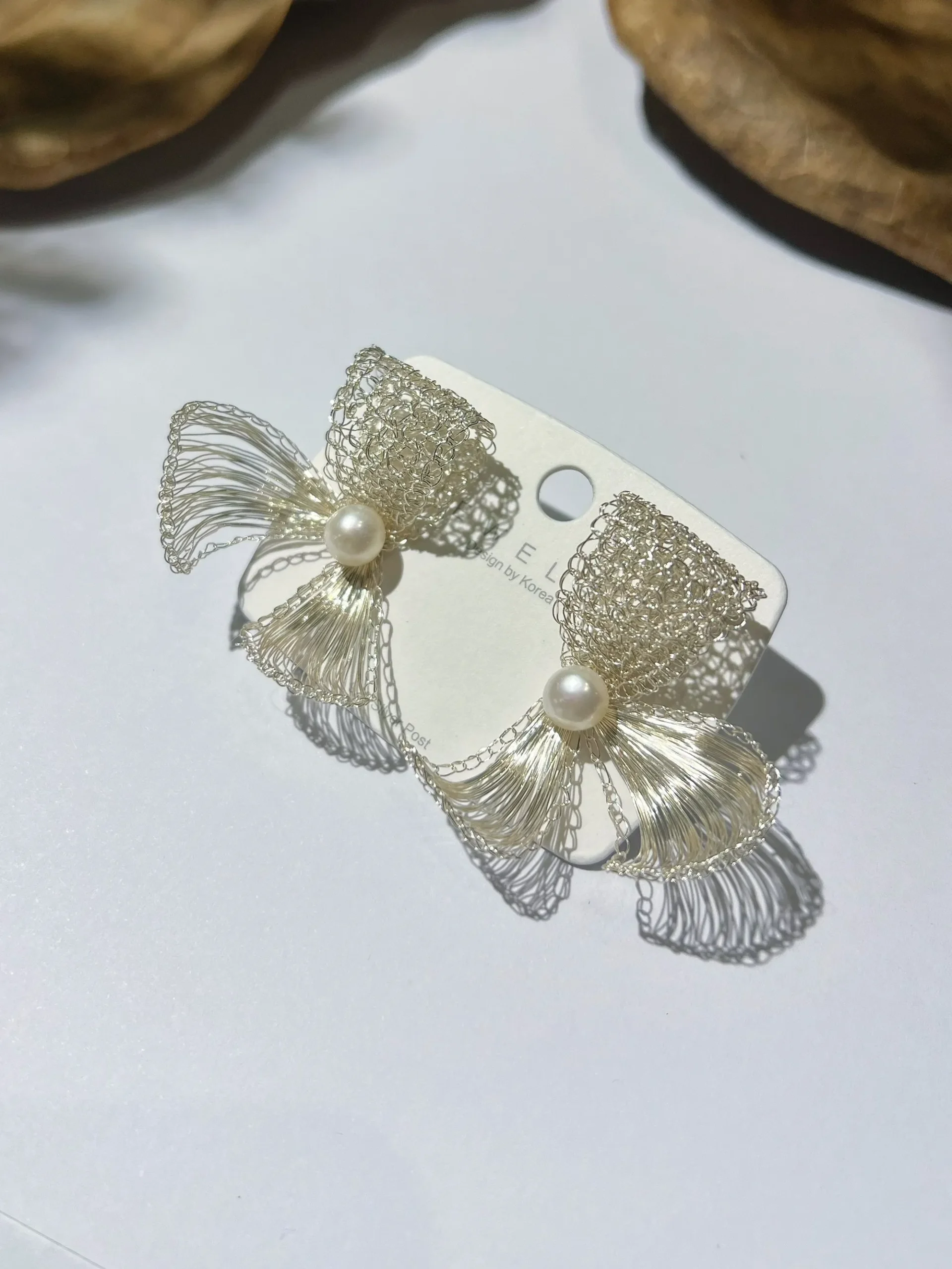 Pair of handmade silver-tone wire bow earrings on a display card