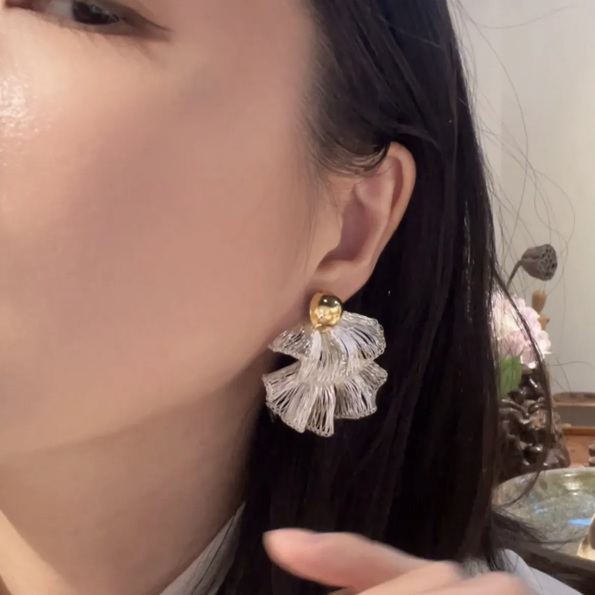 Sculptural handwoven silver-tone wire fan earring worn on ear