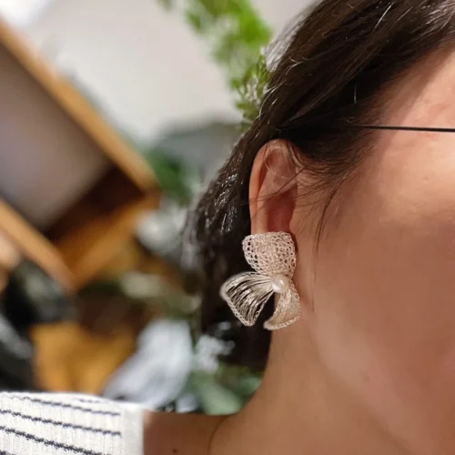 Woman wearing a handmade silver-tone wire bow statement earring
