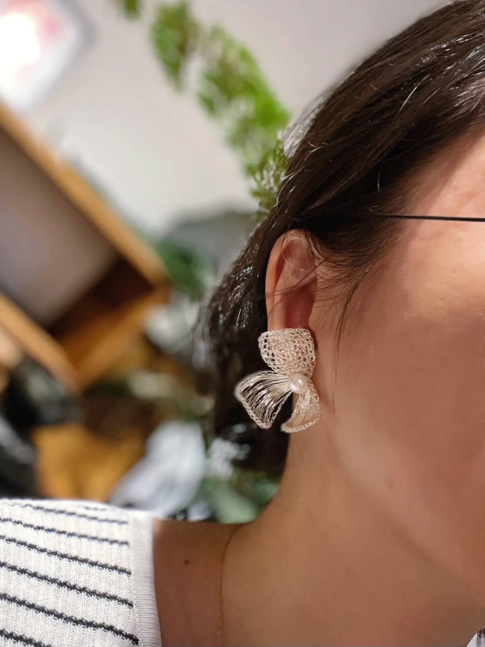 Woman wearing a silver-tone wire bow statement earring