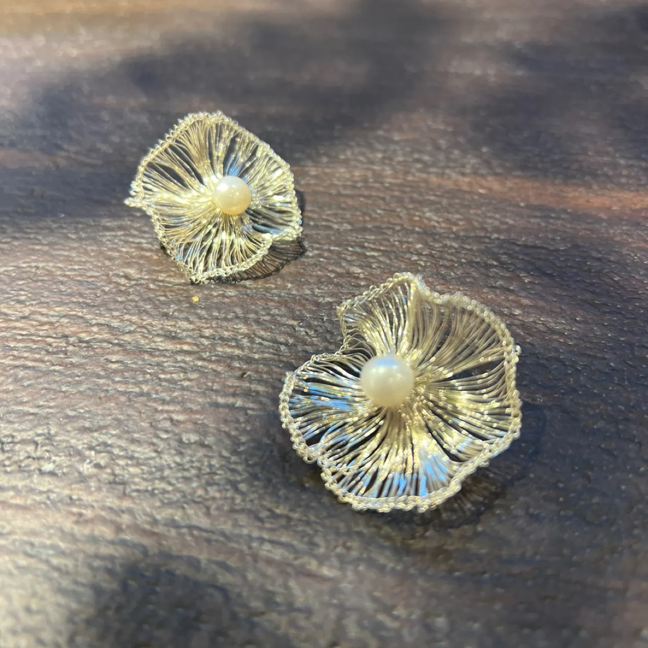 Artisan collection of silver-tone wire floral earrings displayed on dried leaves