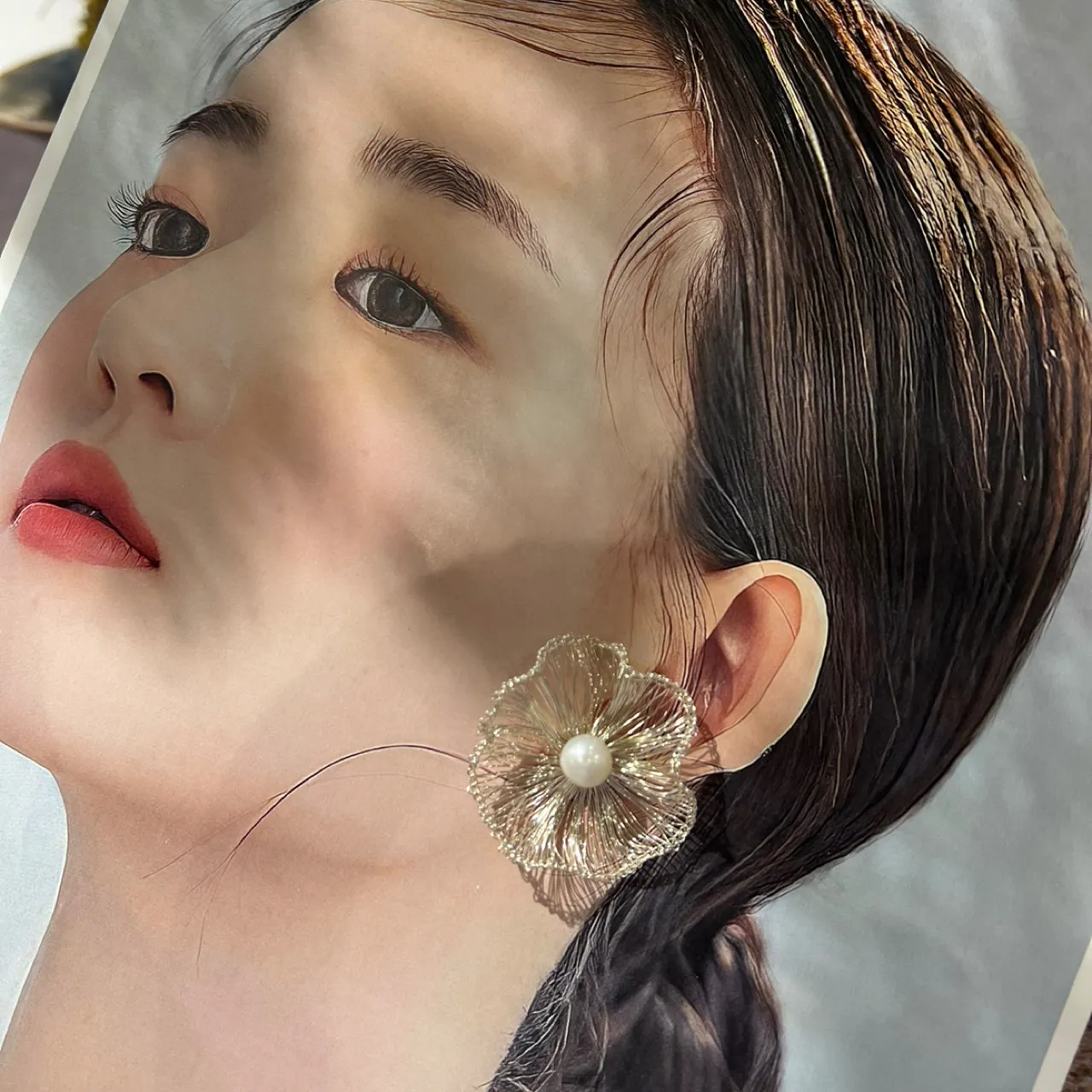 Silver-tone wire flower earring styled against a fashion portrait