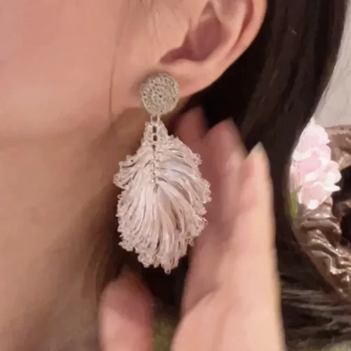 Woman wearing a handmade silver-tone wire leaf statement earring