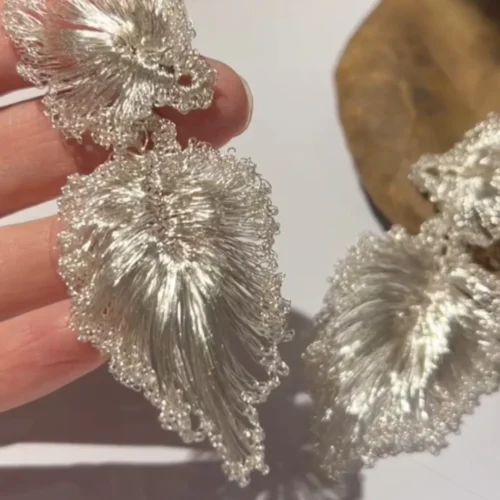 Close-up of handwoven silver-tone wire ginkgo leaf earrings
