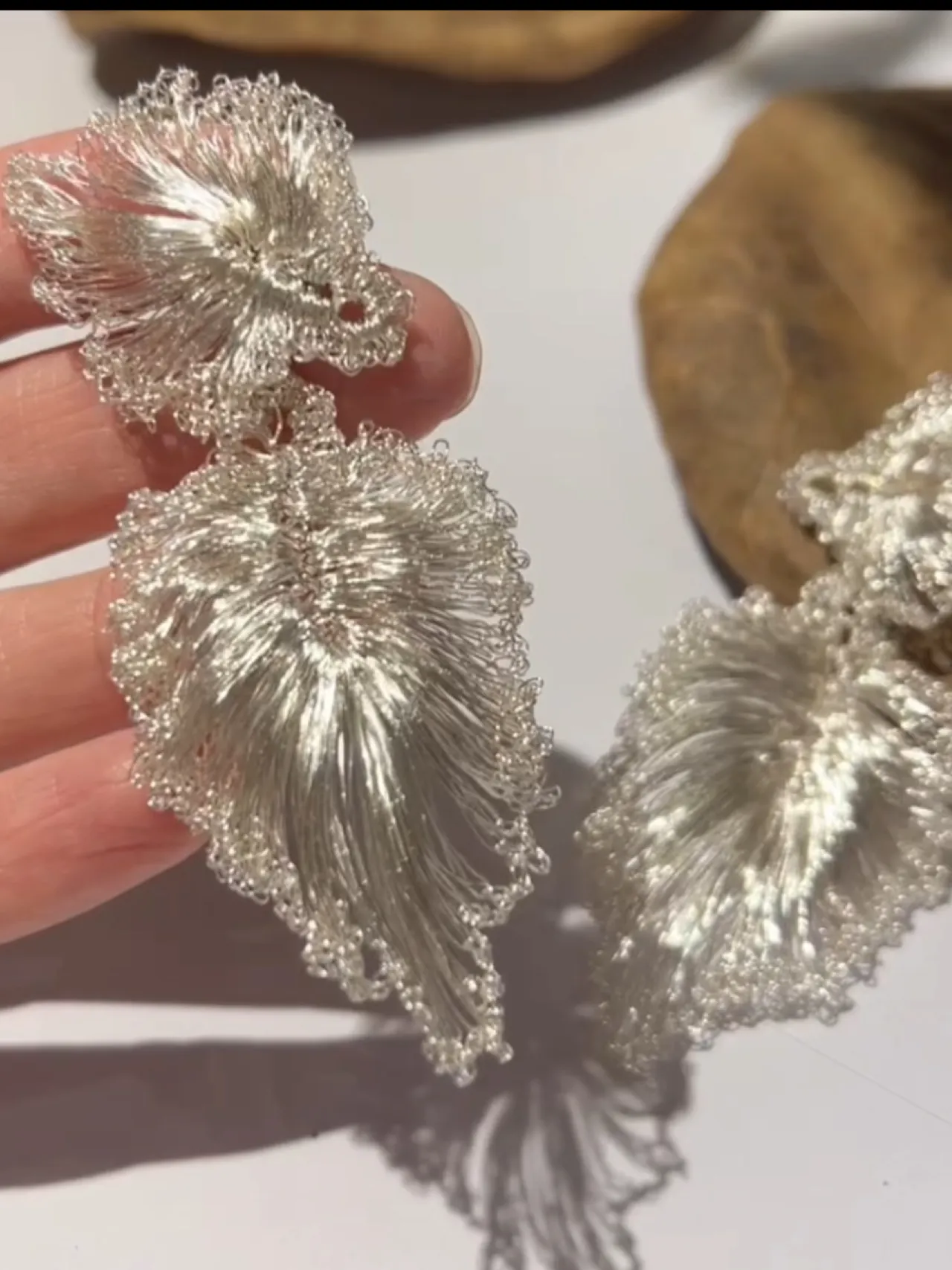 Close-up of handwoven silver-tone wire ginkgo leaf earrings