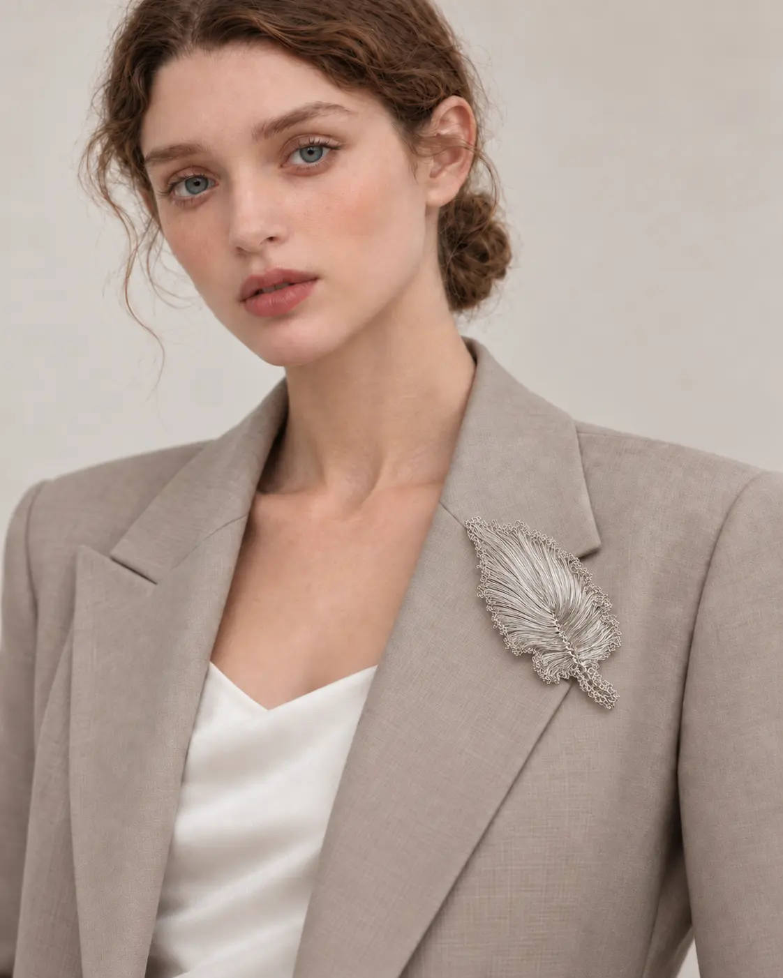 Woman wearing OREYNE handwoven silver-tone ruffled leaf brooch on a blazer