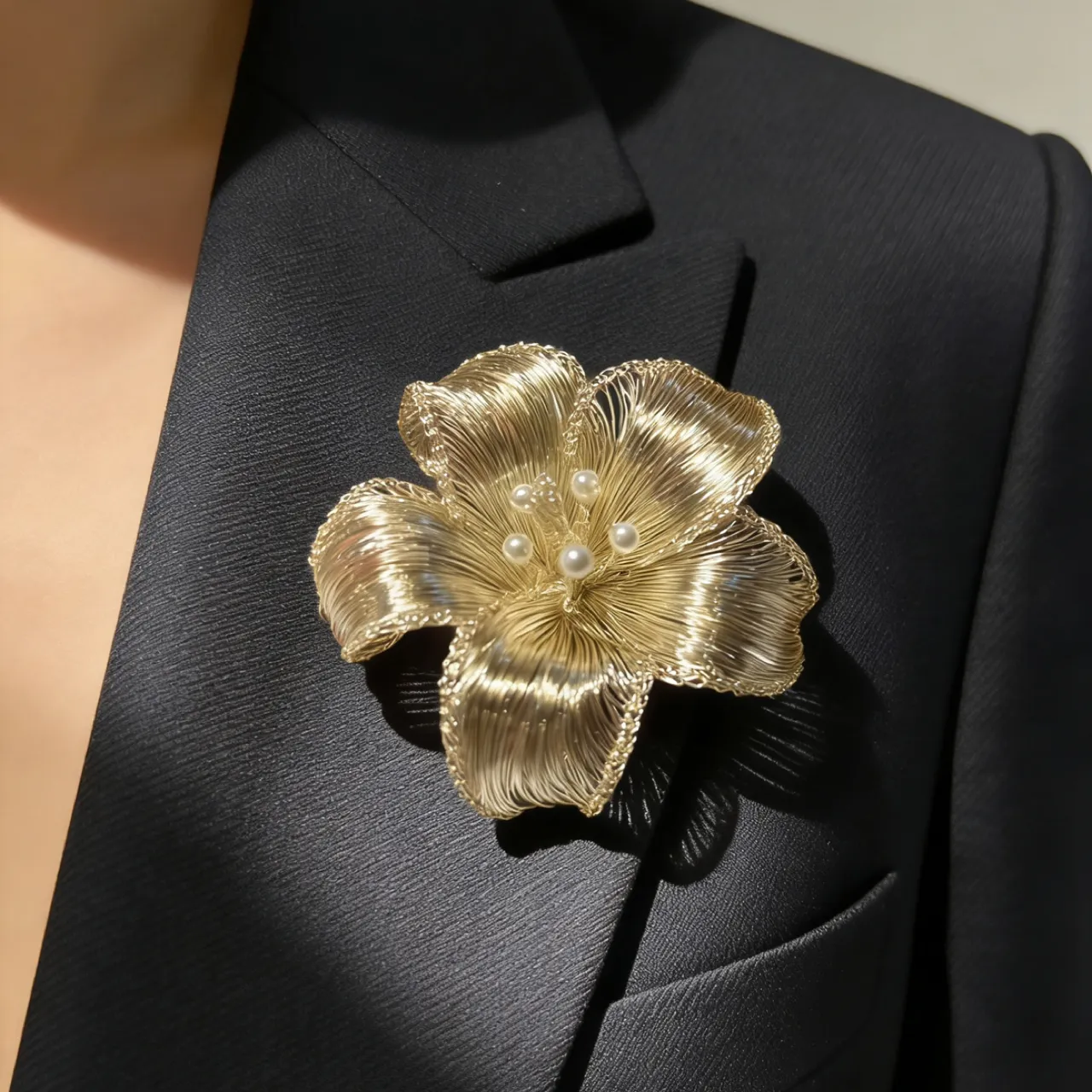 OREYNE sculptural handwoven wire flower brooch worn on a black blazer