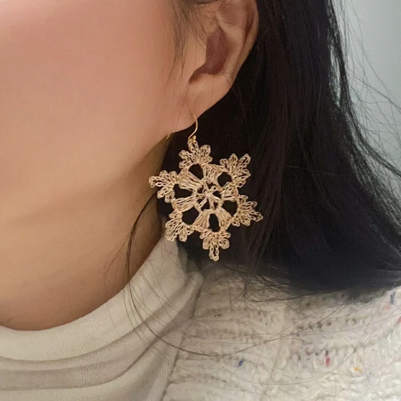 Gold-tone sculptural wire earring worn close-up