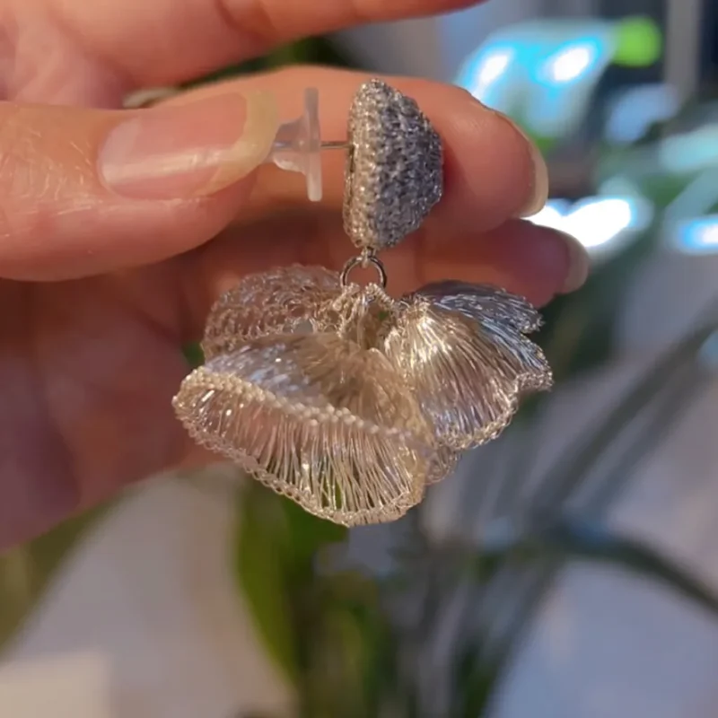 Elara Fold silver-tone handwoven sculptural earring held in hand
