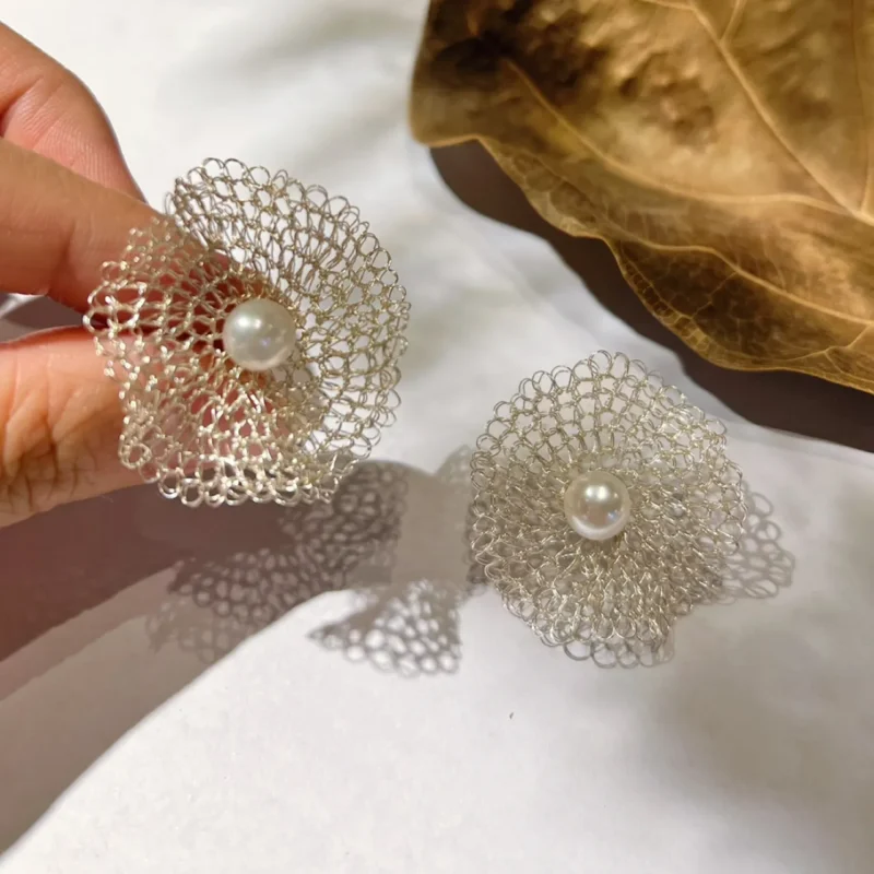 Handheld pair of handwoven Fine Silver-Plated Copper Wire flower earrings with pearl-look center accents