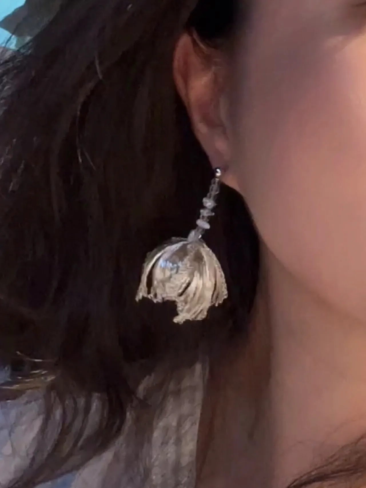 Silver-tone bell earring with a faceted detail worn close-up