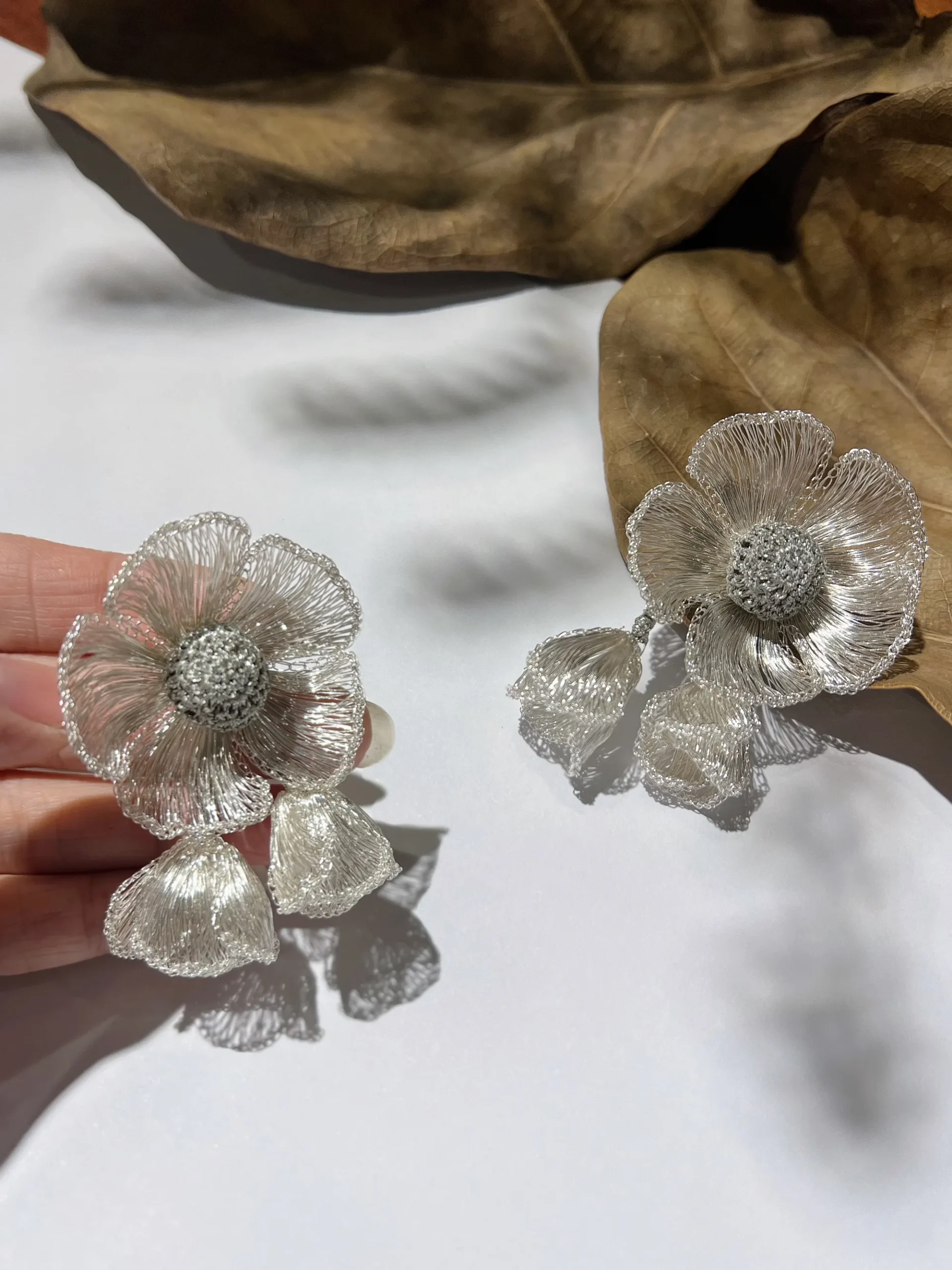 Pair of silver-tone handwoven wire flower earrings with textured centers and removable double petal dangles