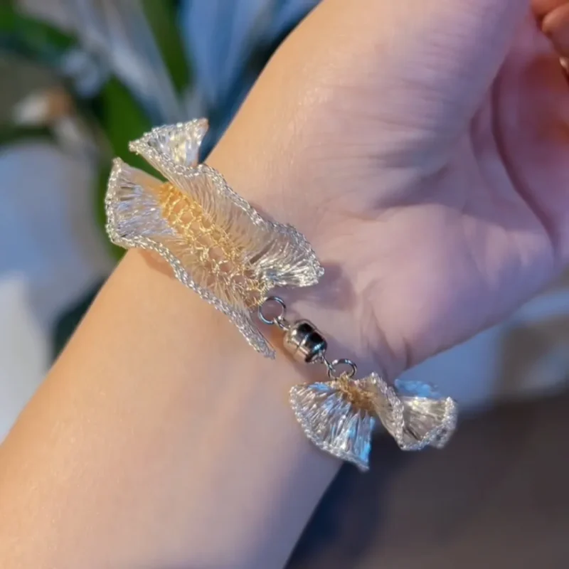 Open silver-tone and gold-tone handwoven wire bracelet showing its end connection and layered ruffled structure
