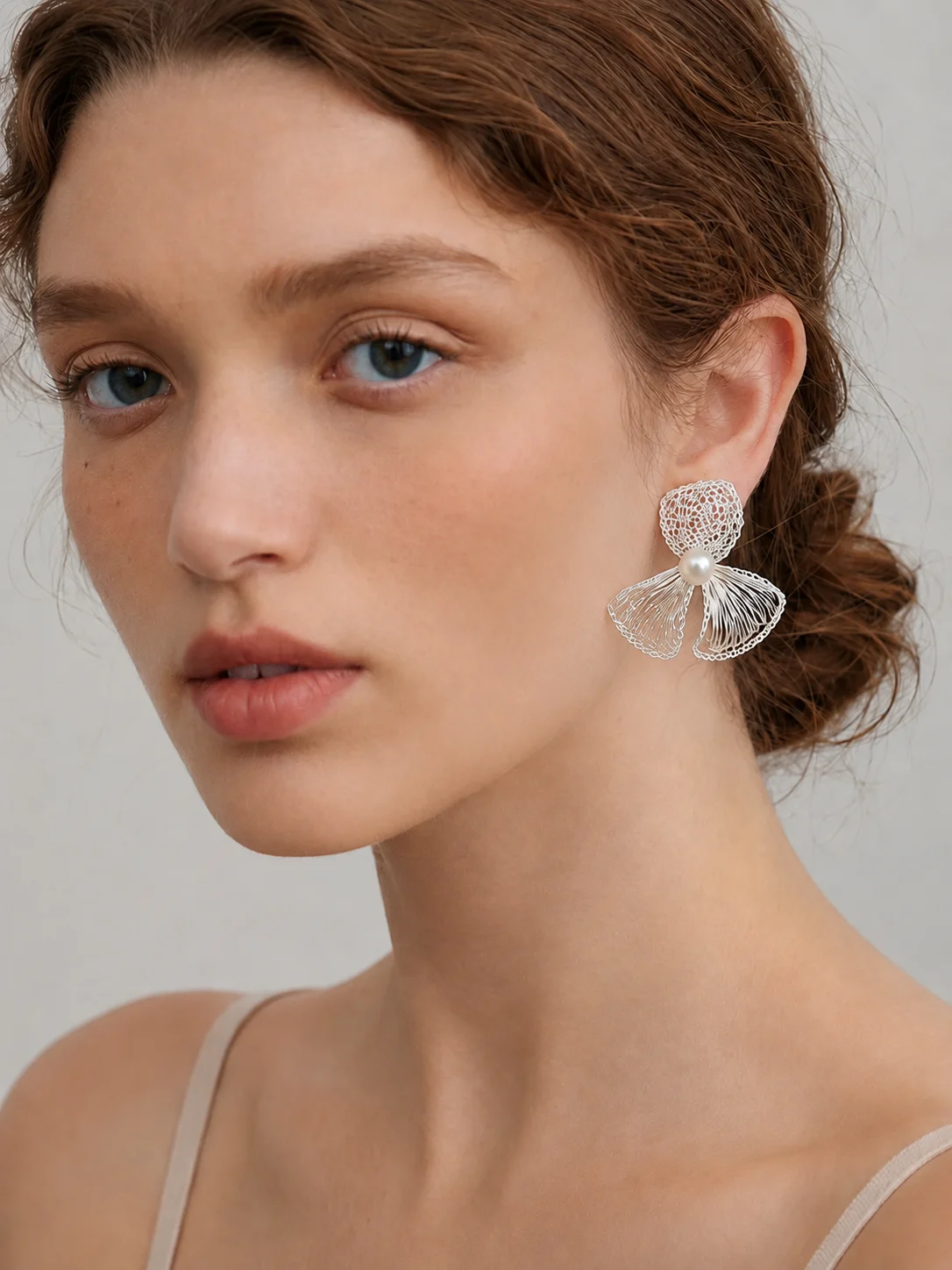 Woman wearing a handmade openwork bow statement earring