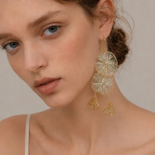 Close-up of OREYNE handwoven gold-tone petal tassel earrings held in hand