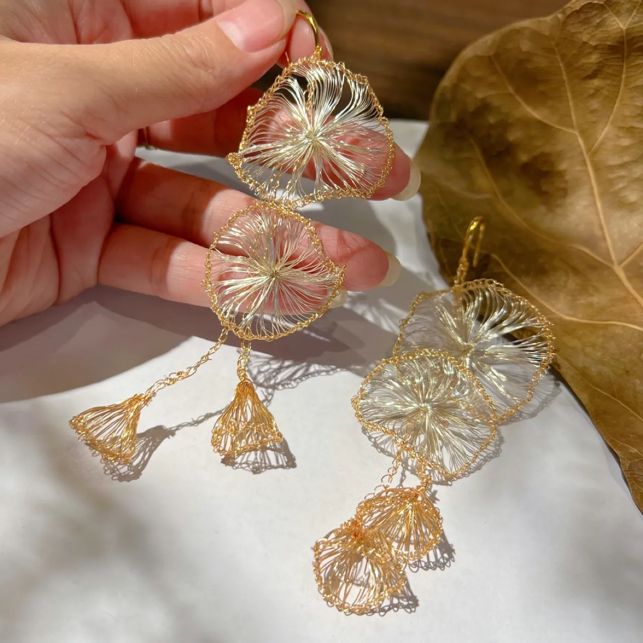 Close-up detail of OREYNE handwoven gold-tone petal tassel earrings