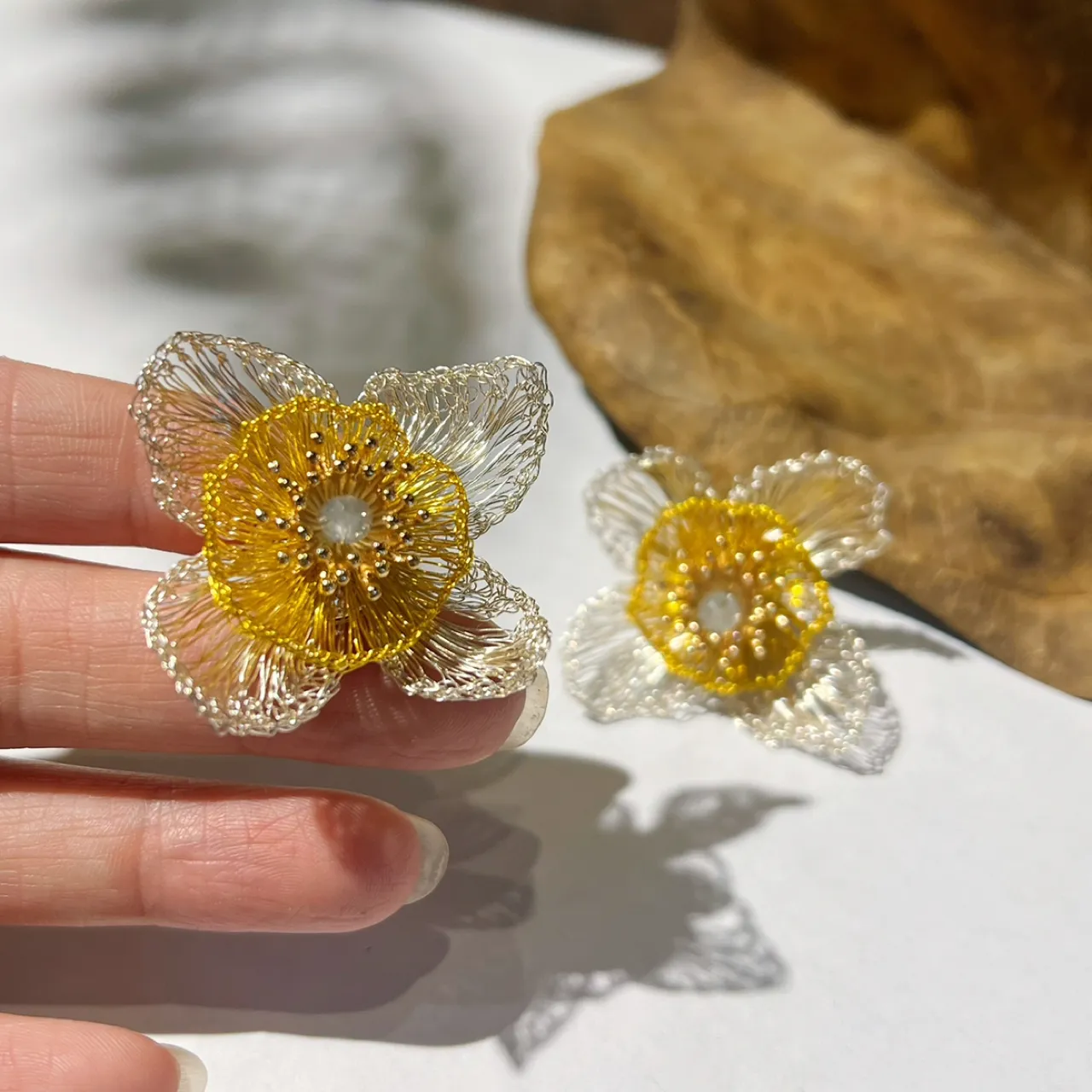 Close-up of OREYNE silver-tone and gold-tone handwoven flower earrings