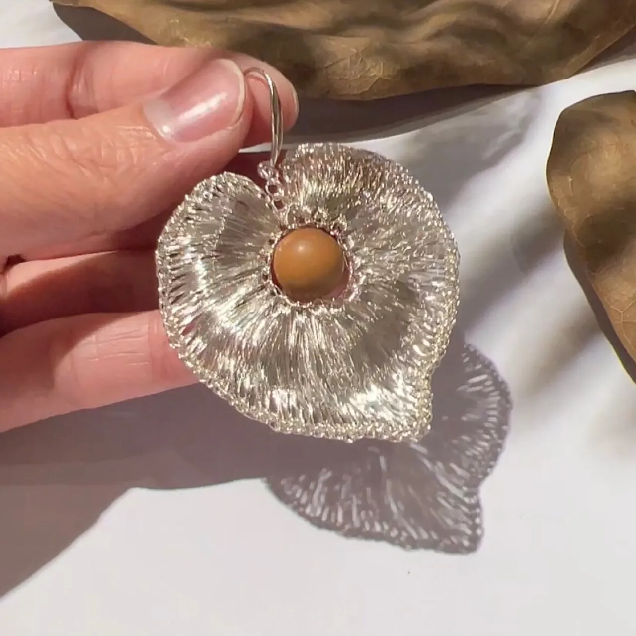 Close-up detail of OREYNE handwoven silver-tone heart drop earring