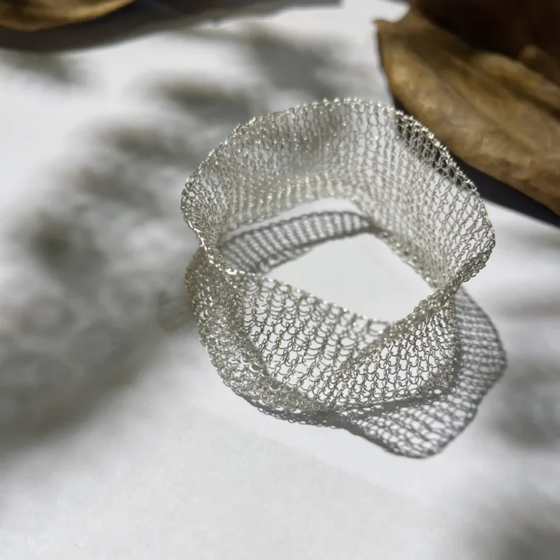 Close-up detail of OREYNE handwoven silver-tone mesh cuff bracelet