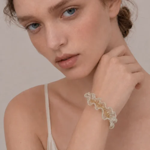 Model wearing OREYNE handmade silver wire sculptural bracelet with gold-toned woven details