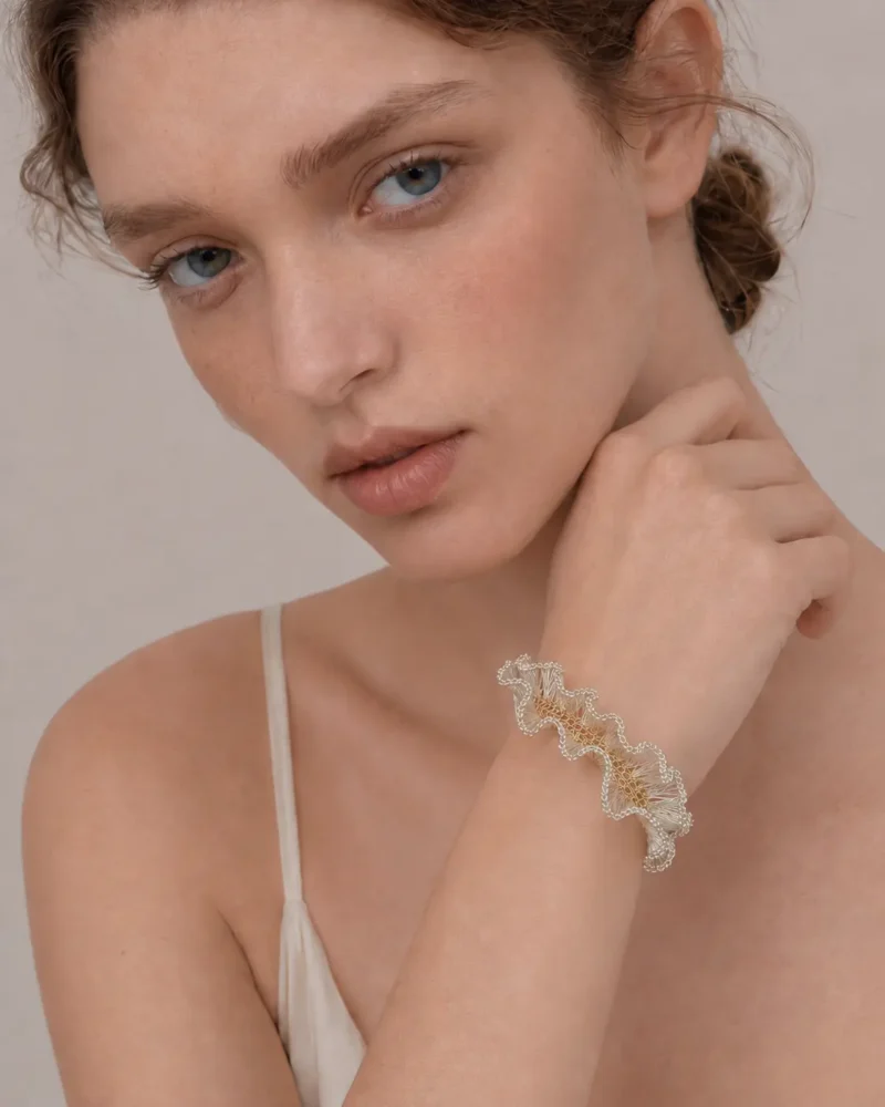 Model wearing OREYNE handmade silver wire sculptural bracelet with gold-toned woven details