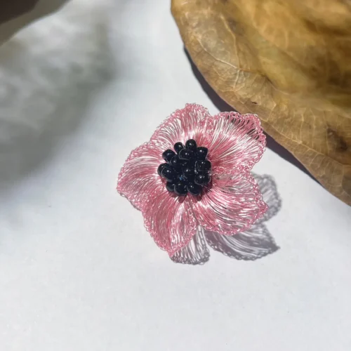 Pink handwoven wire anemone-inspired statement earring with a clustered black bead center