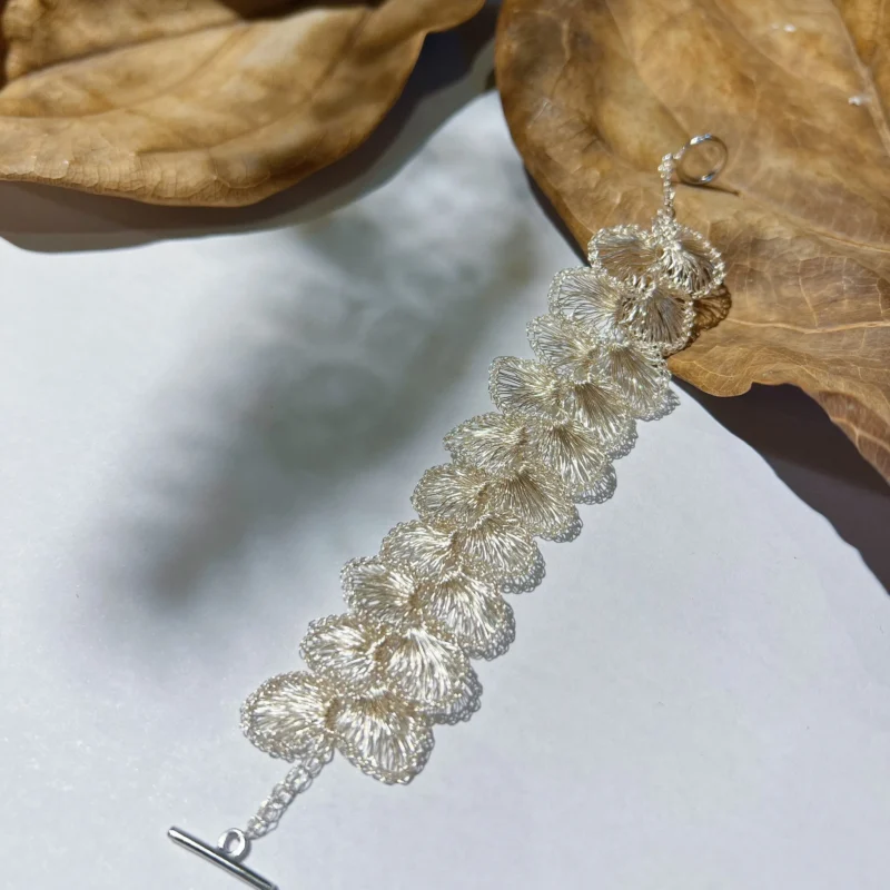 Full view of a sculptural floral bracelet crafted from Fine Silver-Plated Copper Wire with linked handwoven blossoms and toggle closure