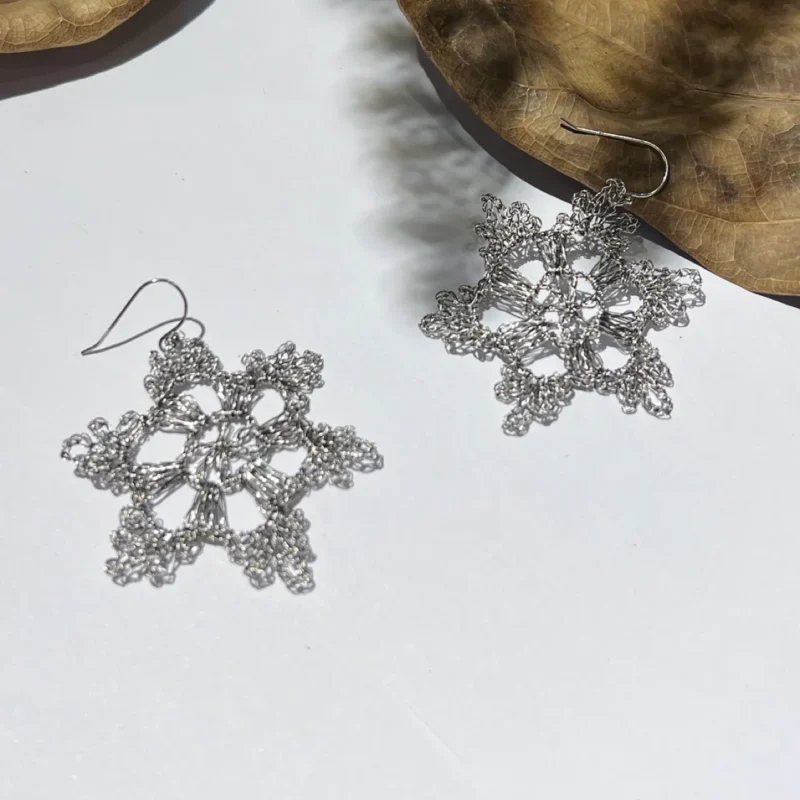 Pair of handwoven Fine Silver-Plated Copper Wire earrings with an open lace-like radial structure and sculptural looped edges.