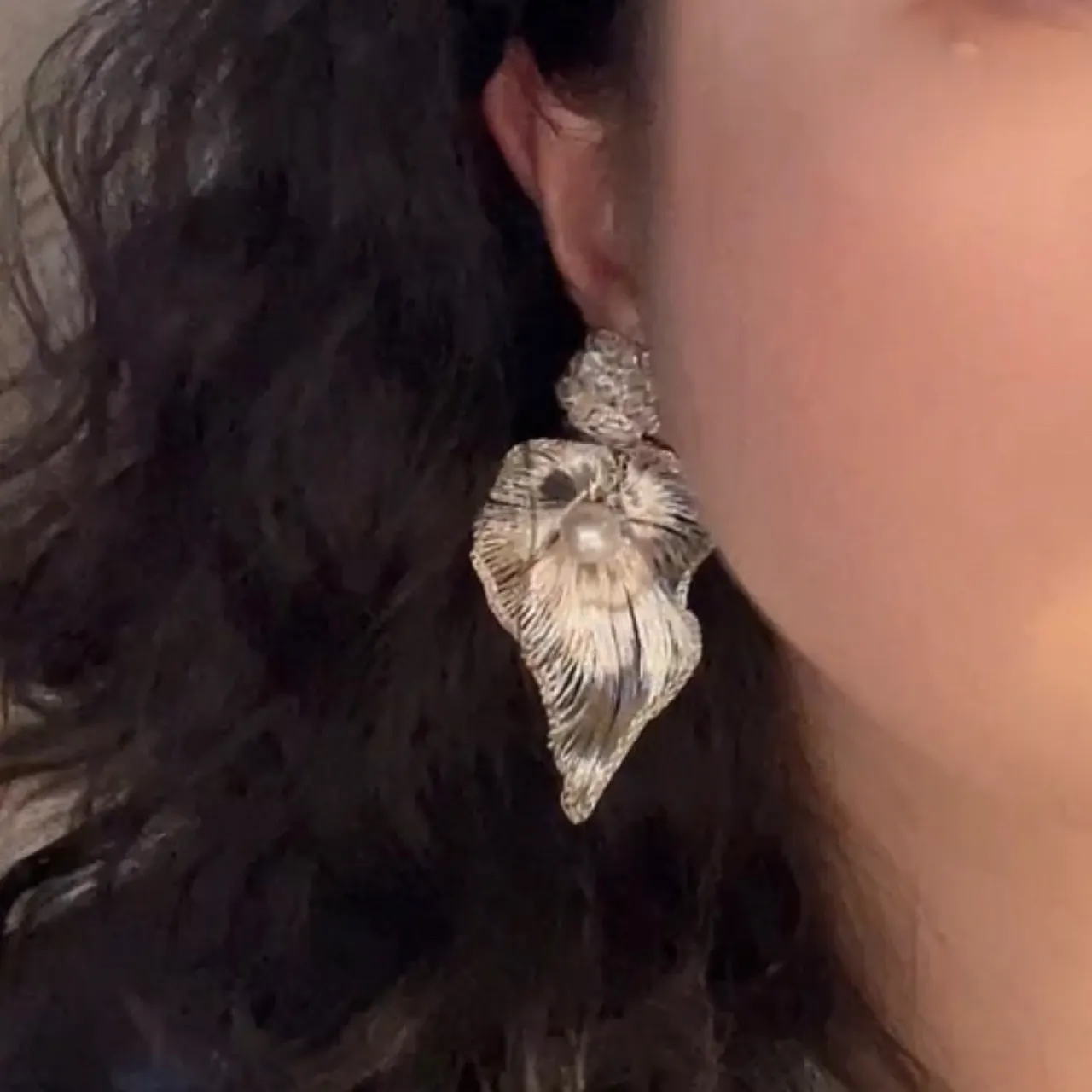 Layered silver-tone OREYNE earring worn close-up