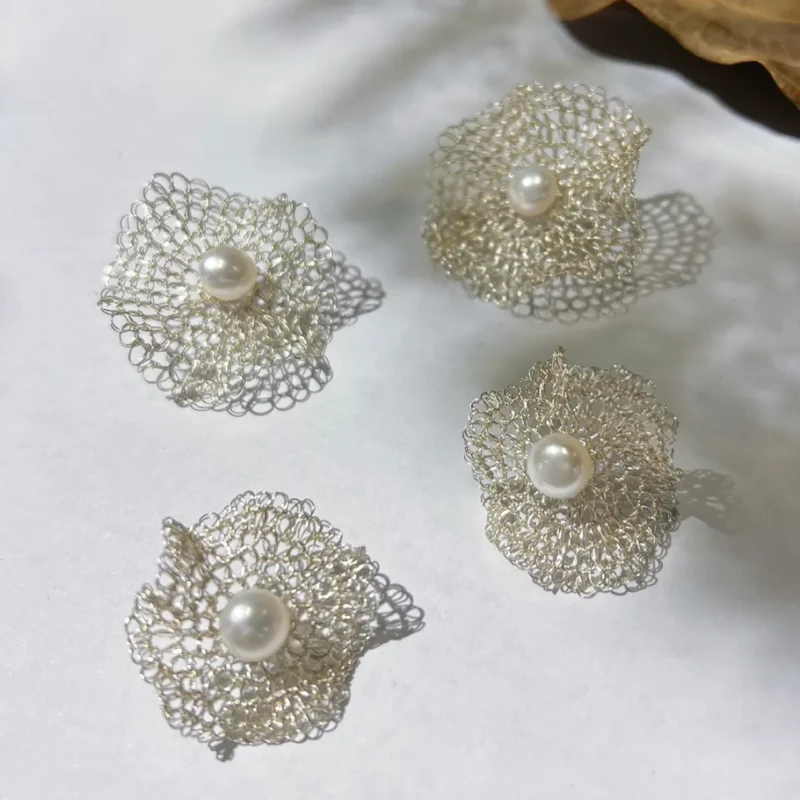 Silver-tone sculptural wire flower earrings arranged together with pearl-look center details