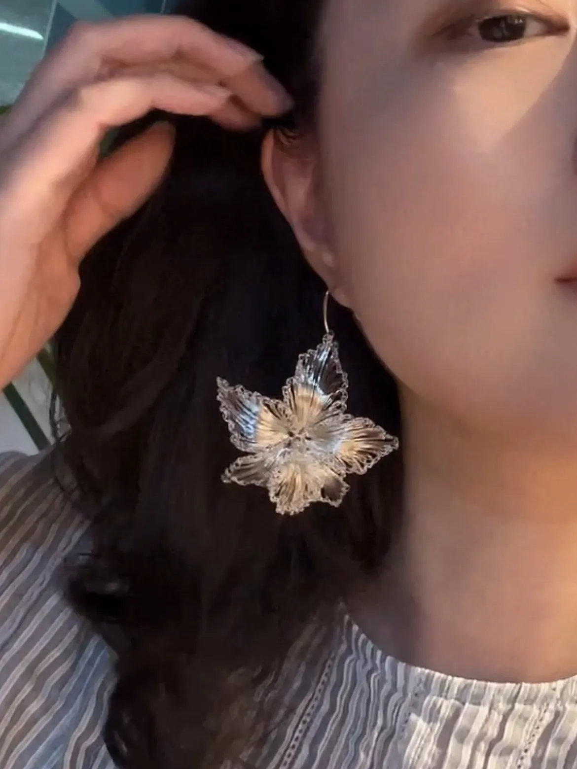 Silver-tone woven blossom earring worn in soft light