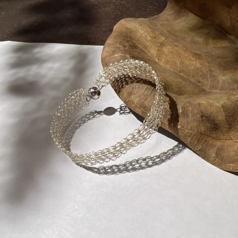 Curved Fine Silver-Plated Copper Wire mesh bracelet showing its open woven band and round ball-style clasp