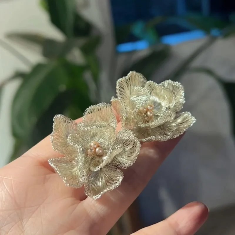 Handheld view of OREYNE Cotton Rose sculptural stud earrings