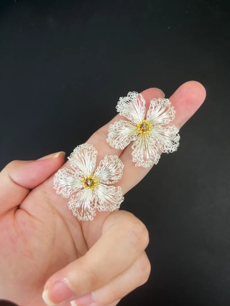 Close-up handheld view of OREYNE White Strawberry Blossom earrings